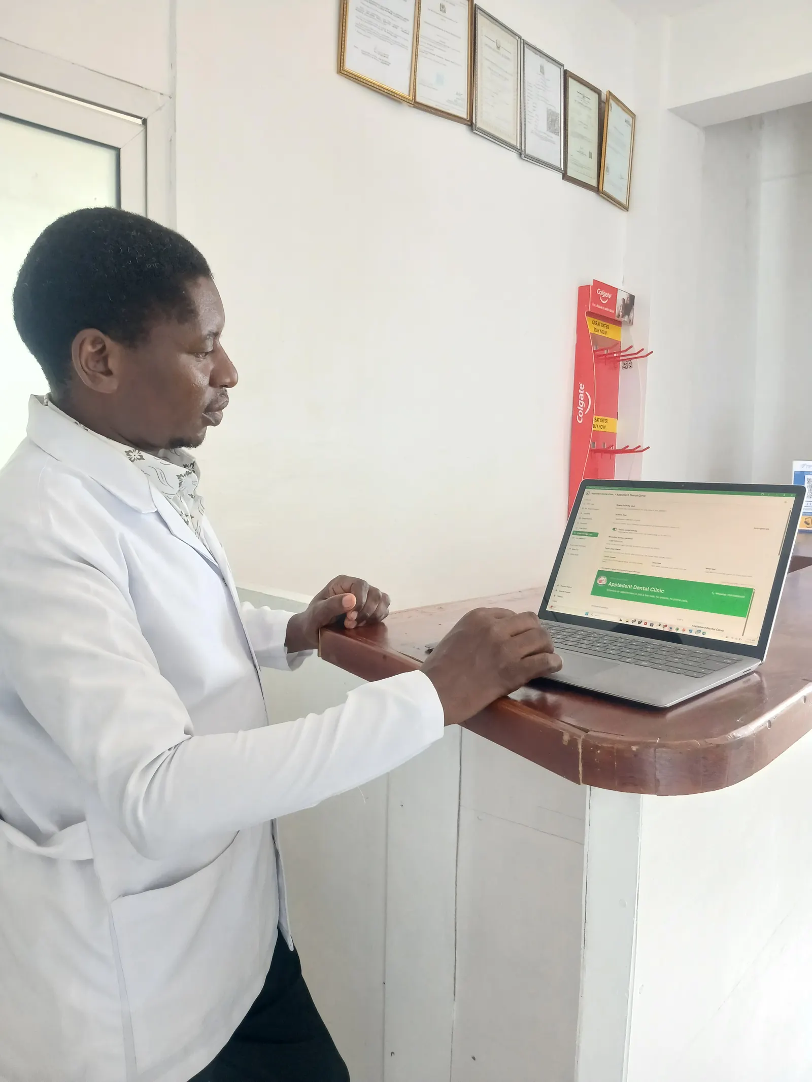 Dr. Shunu, CEO of Appledental Clinic, using AfyaBooking on a laptop