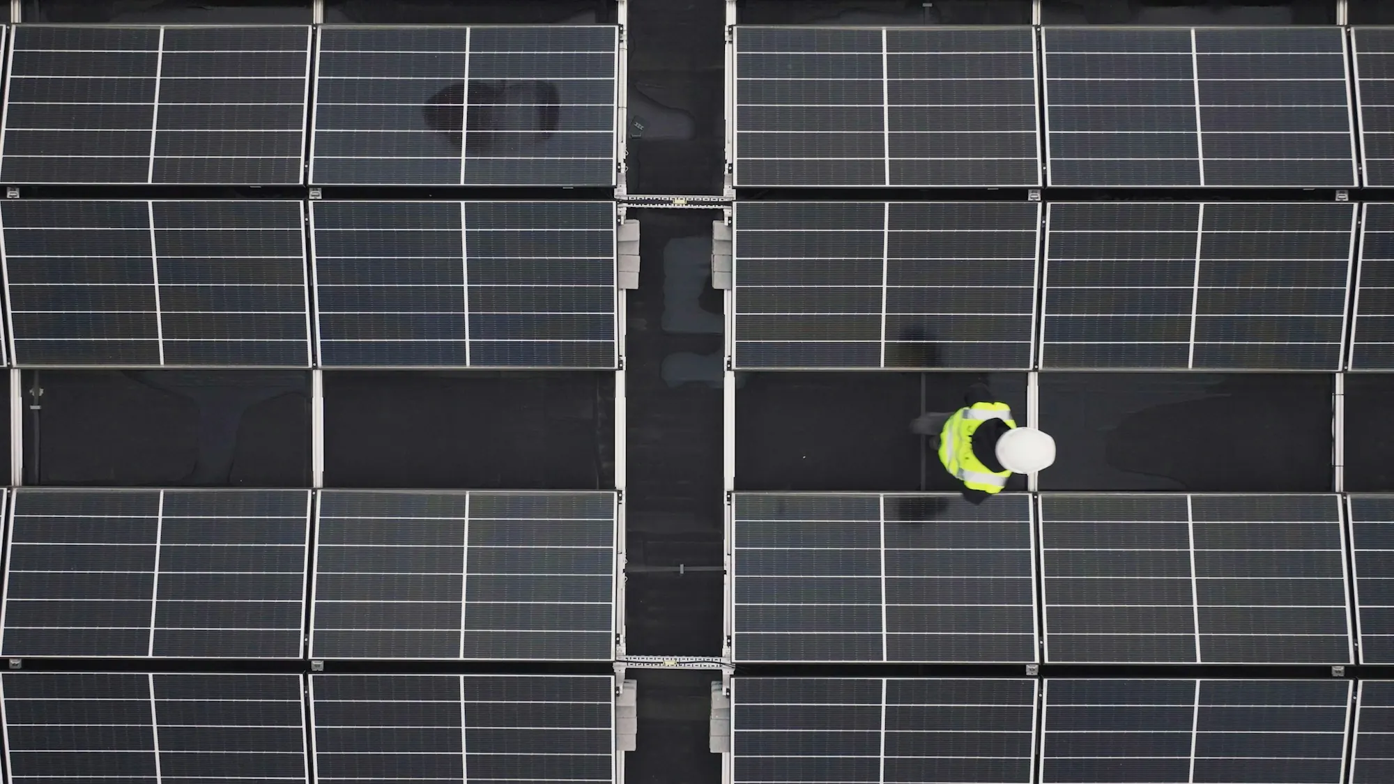 Aerial view of a technician walking between rows of solar panels